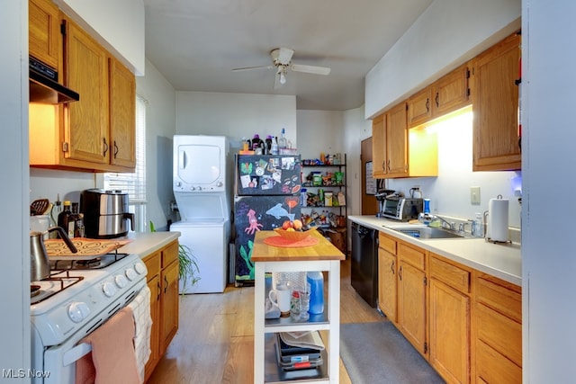 kitchen with black dishwasher, sink, ceiling fan, stacked washing maching and dryer, and light hardwood / wood-style flooring