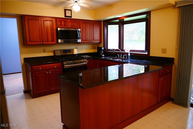 kitchen featuring sink, appliances with stainless steel finishes, dark stone counters, and kitchen peninsula