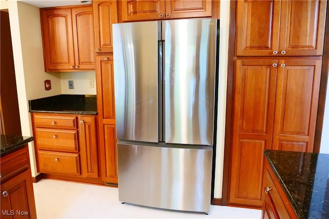 kitchen featuring stainless steel fridge and dark stone countertops