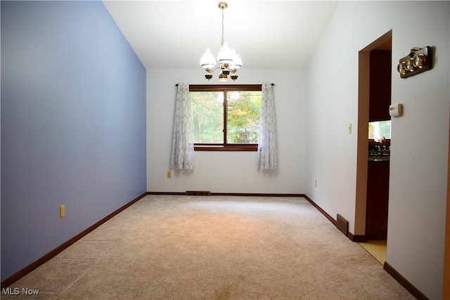 carpeted spare room with a notable chandelier