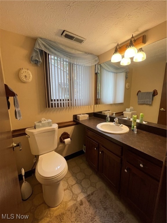 bathroom with vanity, toilet, and a textured ceiling