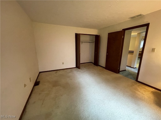 unfurnished bedroom featuring light carpet, a closet, and a textured ceiling