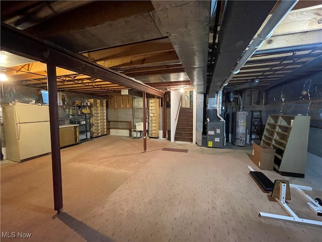 basement featuring water heater, heating unit, and white refrigerator