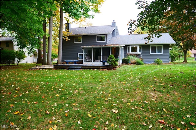 rear view of property featuring a deck, a lawn, and a sunroom