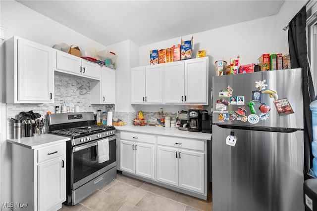 kitchen with appliances with stainless steel finishes, light tile patterned flooring, white cabinets, and tasteful backsplash