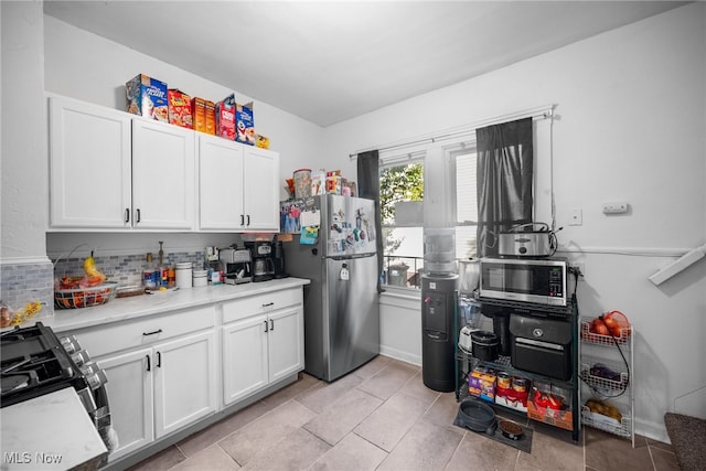 kitchen featuring appliances with stainless steel finishes, decorative backsplash, white cabinets, and light tile patterned floors