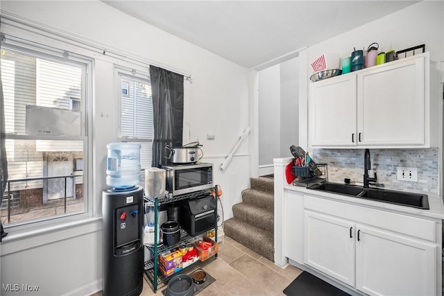 1633 Hopkins Ave, Lakewood, OH 44107 - kitchen with a sink, stainless steel microwave, white cabinetry, and decorative backsplash