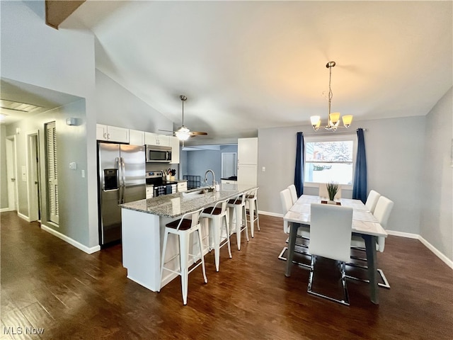 kitchen featuring stone countertops, dark hardwood / wood-style floors, a breakfast bar area, white cabinets, and appliances with stainless steel finishes