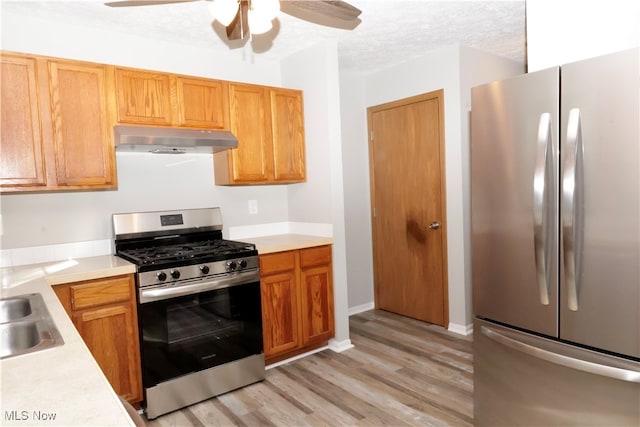 kitchen featuring appliances with stainless steel finishes, light hardwood / wood-style flooring, a textured ceiling, and ceiling fan