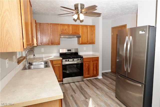 kitchen featuring appliances with stainless steel finishes, a textured ceiling, sink, and light hardwood / wood-style floors