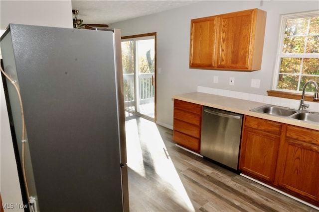 kitchen with light hardwood / wood-style floors, a textured ceiling, appliances with stainless steel finishes, and sink