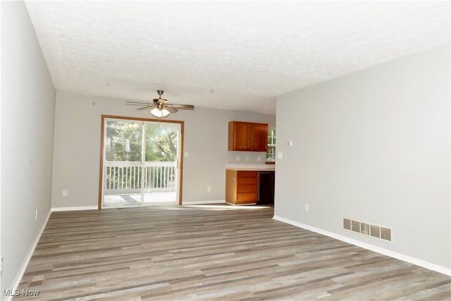 unfurnished living room with light hardwood / wood-style flooring, a textured ceiling, and ceiling fan