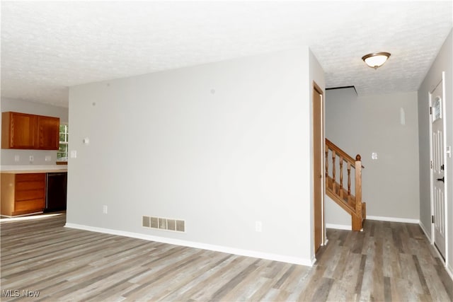 unfurnished living room with light hardwood / wood-style flooring and a textured ceiling