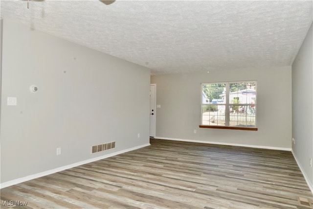 unfurnished room with a textured ceiling and light hardwood / wood-style flooring