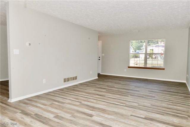 unfurnished room with a textured ceiling and light hardwood / wood-style floors