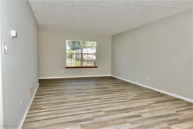 empty room with a textured ceiling and light hardwood / wood-style floors