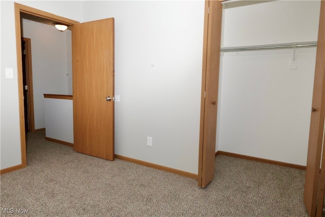 unfurnished bedroom with light carpet and a closet