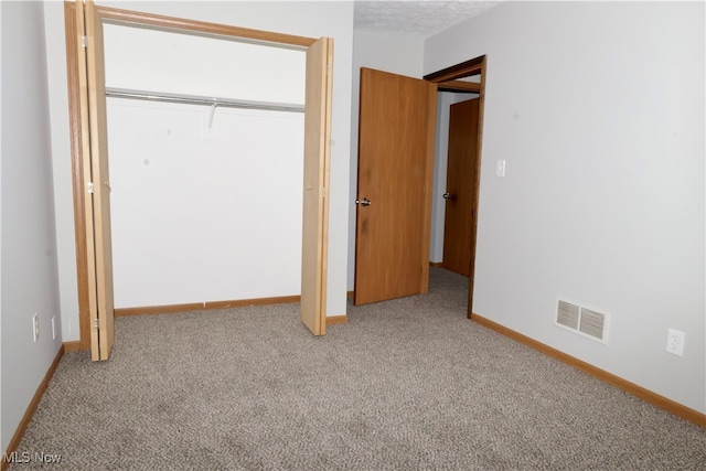 unfurnished bedroom with a closet, carpet floors, and a textured ceiling