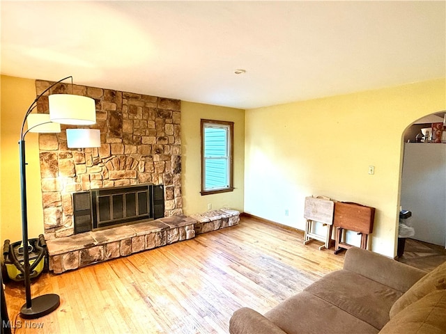 living room with a stone fireplace and hardwood / wood-style flooring