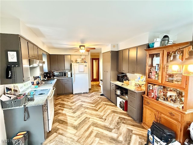 kitchen with light stone counters, ceiling fan, stove, white fridge, and light parquet floors