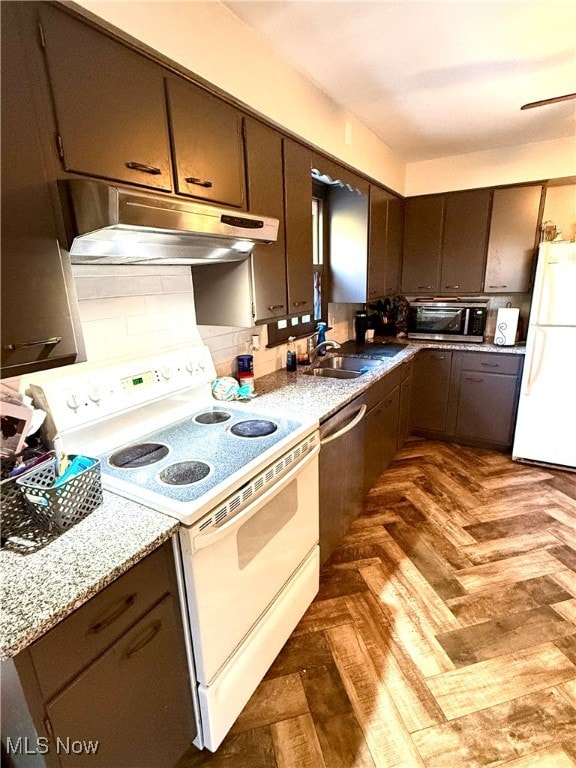 kitchen with dark parquet floors, sink, light stone countertops, white appliances, and tasteful backsplash