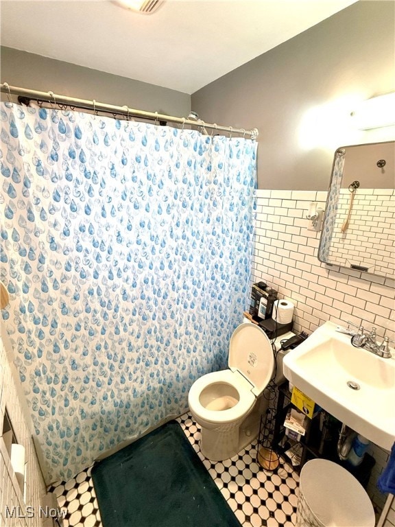 bathroom with toilet, tile walls, and a shower with curtain