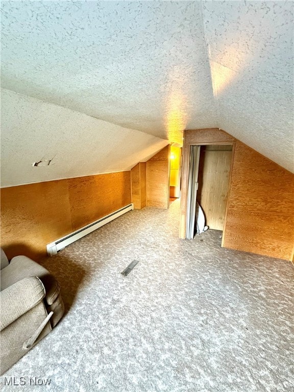 bonus room with carpet flooring, a baseboard radiator, a textured ceiling, vaulted ceiling, and wooden walls