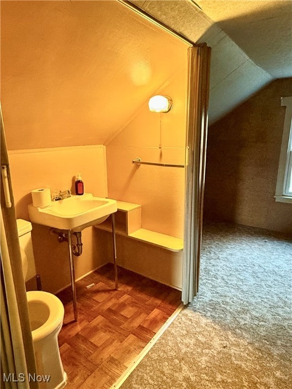 bathroom featuring lofted ceiling, parquet floors, and toilet