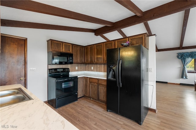 kitchen featuring vaulted ceiling with beams, light hardwood / wood-style flooring, black appliances, and sink