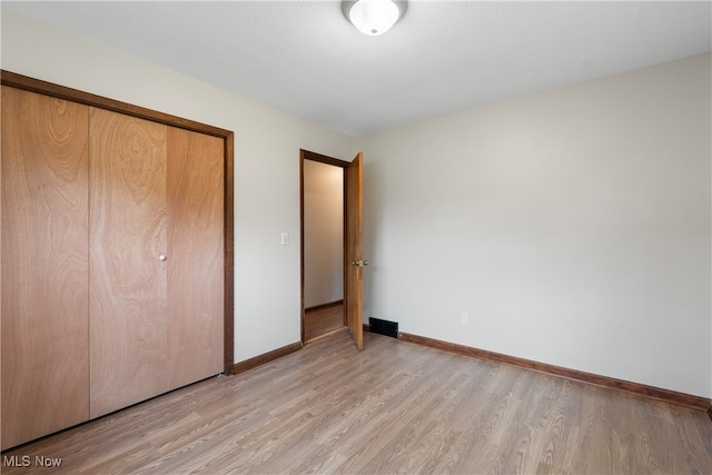 unfurnished bedroom with a closet and light wood-type flooring