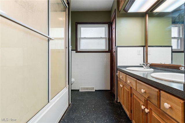 full bathroom with vanity, tile walls, toilet, and plenty of natural light