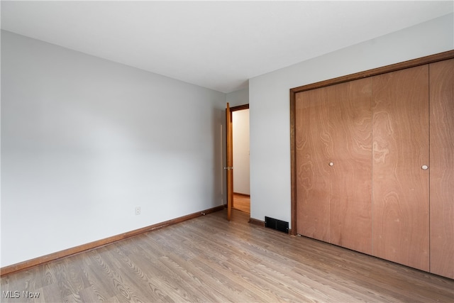 unfurnished bedroom featuring a closet and light wood-type flooring