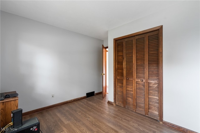 unfurnished bedroom with dark wood-type flooring and a closet