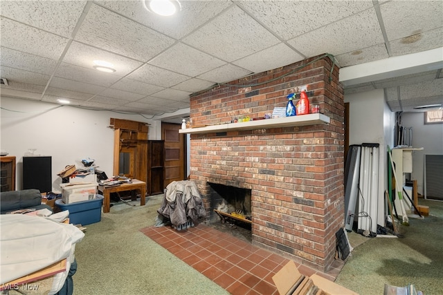 living room with a drop ceiling, dark colored carpet, and a brick fireplace