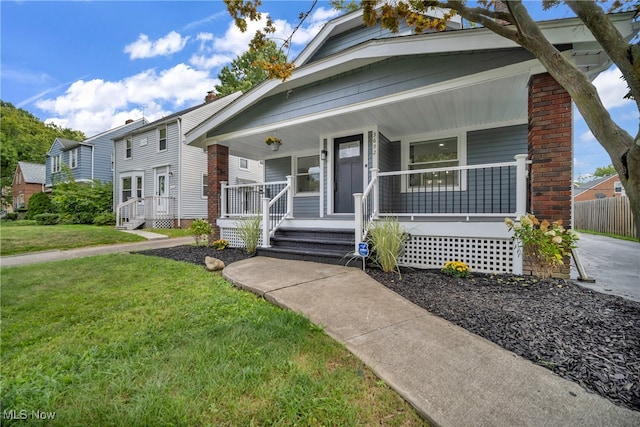 bungalow-style home featuring covered porch and a front yard