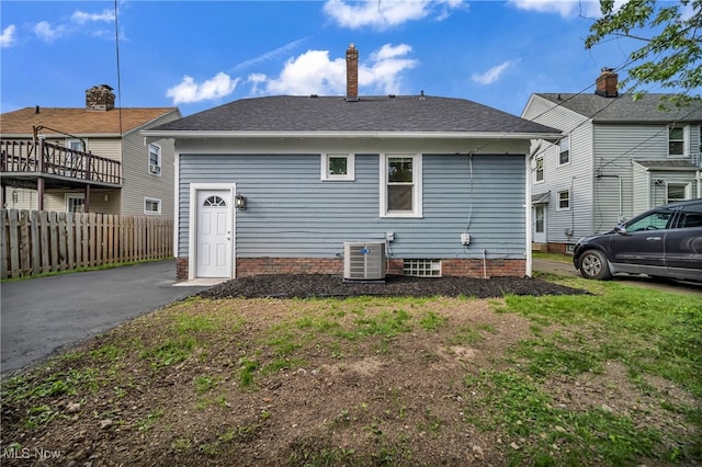 rear view of house with central air condition unit and a yard