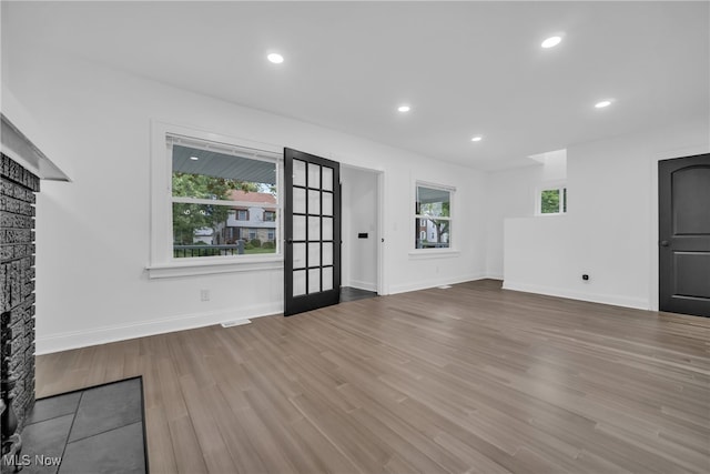 unfurnished living room with wood-type flooring, a fireplace, and a wealth of natural light