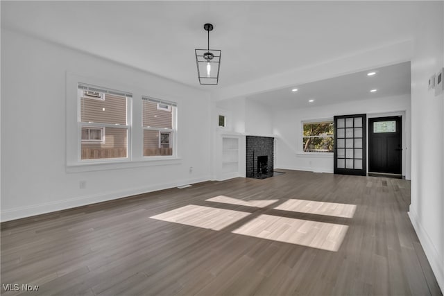 unfurnished living room featuring hardwood / wood-style floors and a brick fireplace