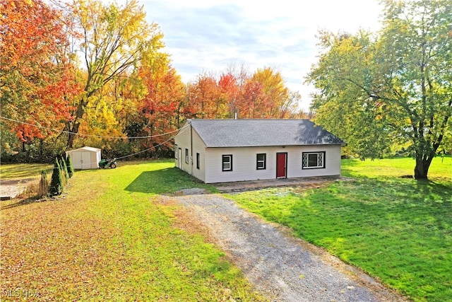 view of front of home with a storage shed and a front lawn