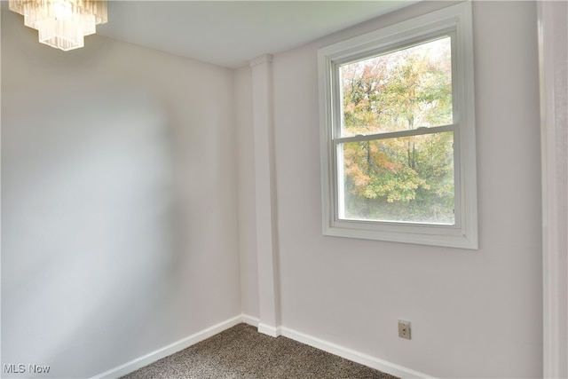 spare room with carpet and an inviting chandelier