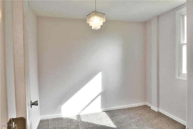 carpeted spare room featuring a notable chandelier