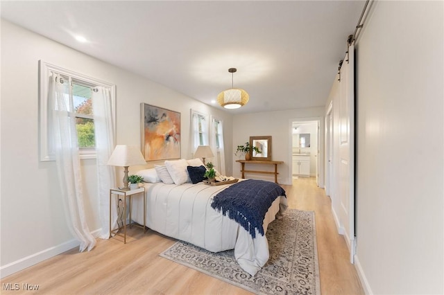 bedroom featuring a barn door and light hardwood / wood-style flooring