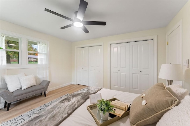 bedroom featuring light hardwood / wood-style flooring, ceiling fan, and multiple closets