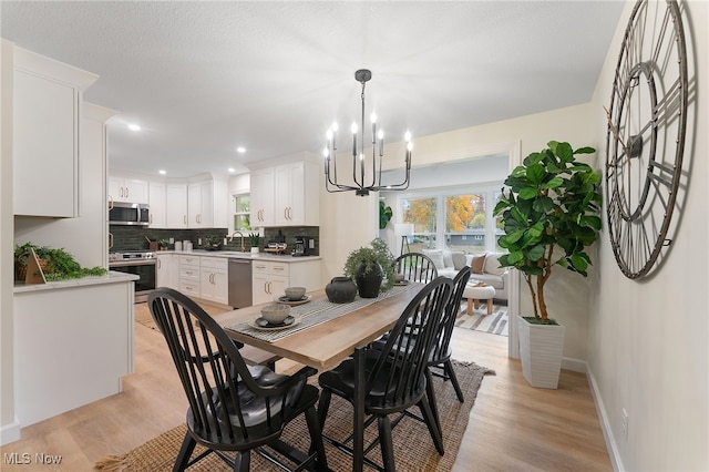 dining area featuring sink, light hardwood / wood-style flooring, and a notable chandelier