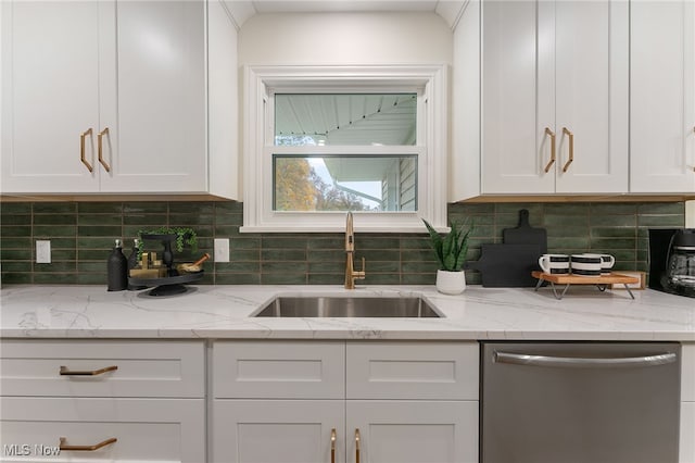 kitchen with backsplash, white cabinetry, sink, and stainless steel dishwasher