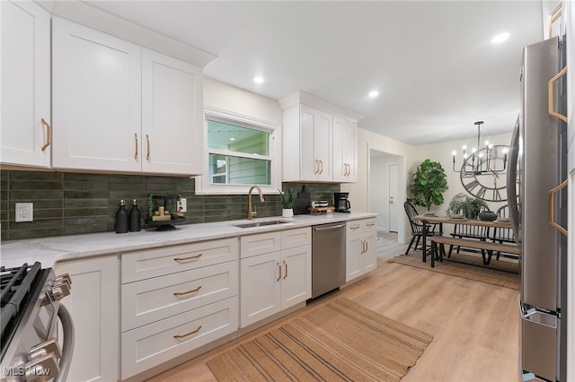 kitchen with sink, stainless steel appliances, a notable chandelier, light hardwood / wood-style floors, and white cabinets