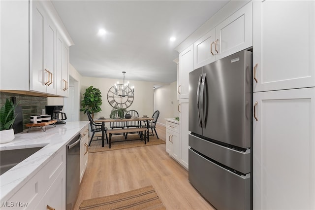 kitchen featuring appliances with stainless steel finishes, light hardwood / wood-style flooring, white cabinetry, and decorative light fixtures