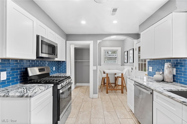 kitchen with white cabinetry, tasteful backsplash, stainless steel appliances, and light stone counters