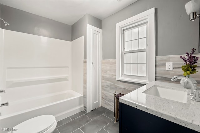 full bathroom with vanity, toilet, and tile walls