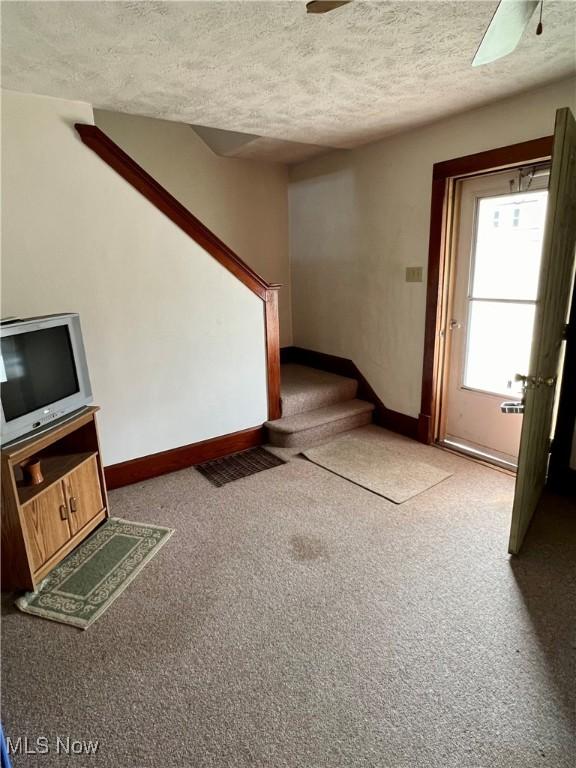1208 N 4th St, Toronto, OH 43964 - unfurnished living room with stairs, carpet flooring, a textured ceiling, a ceiling fan, and baseboards